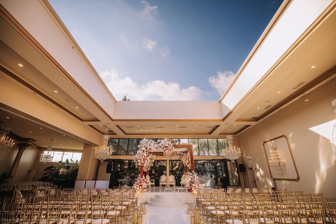 Ceremony beneath the glass ceiling with floral arch